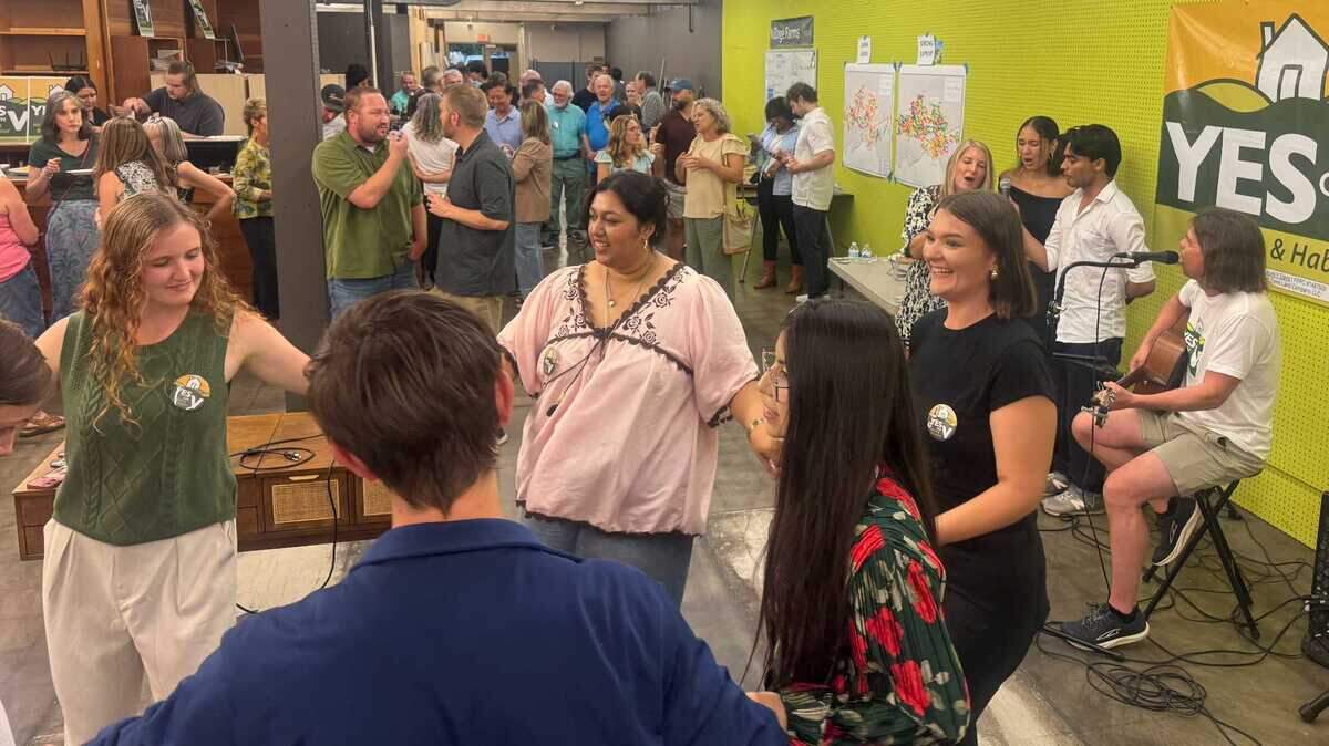 Douglas Buzbee and Rochelle Swanson, at right, sing “Closer to Fine” by the Indigo Girls and dance with campaign interns as results trickled in for Measure V, the ballot referendum for Davis residents to approve the Village Farms development on Tuesday, June 2, 2026.