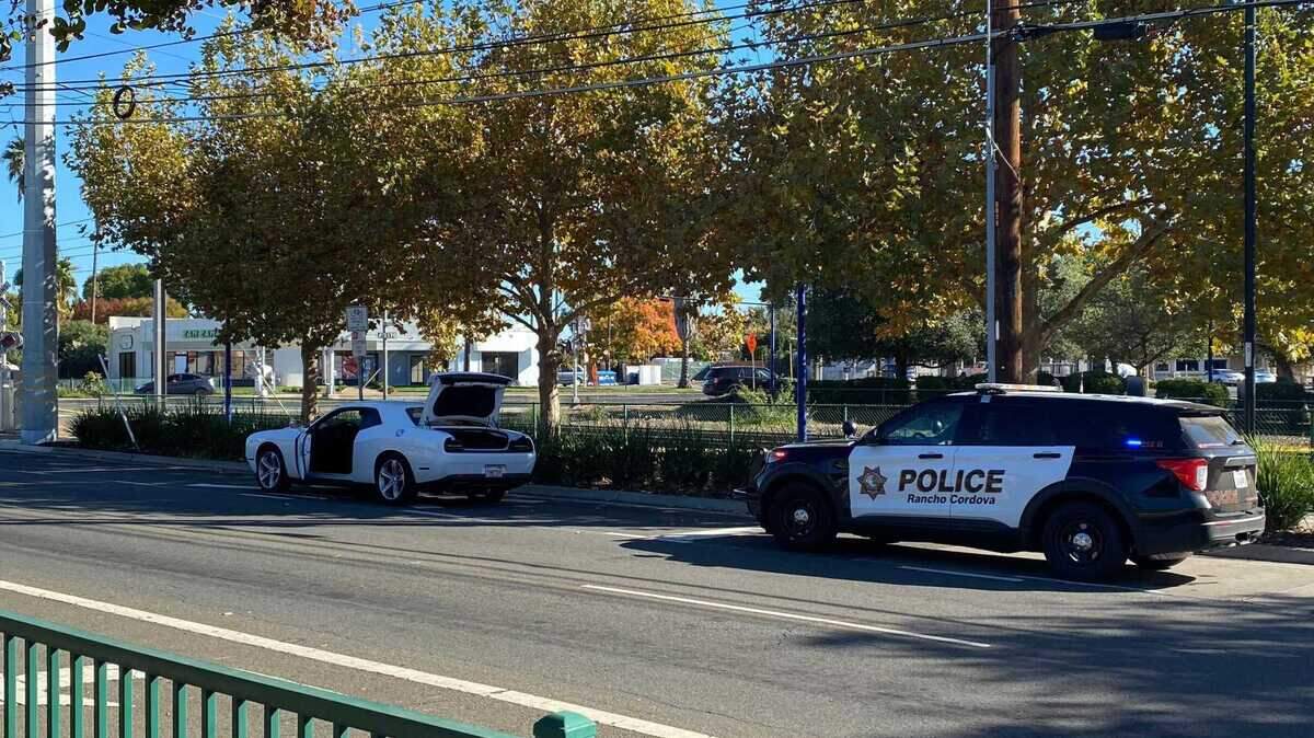 A Dodge Challenger and a Rancho Cordova police vehicle are seen on Folsom Boulevard near Mather Field Road following an officer-involved shooting Monday, Nov. 20, 2023. The Sacramento County Sheriff’s Office, which contracts police services for the city, said two deputies fired on a woman.
