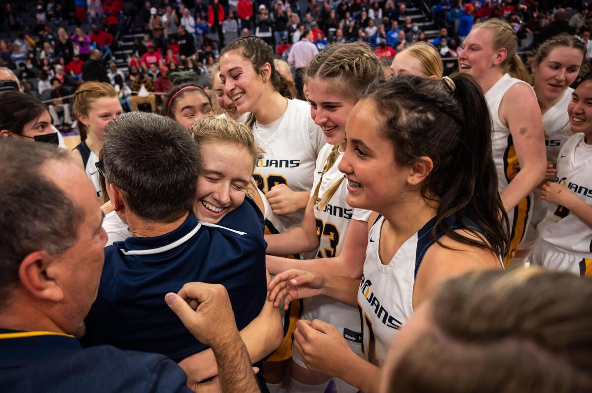 Oak Ridge Trojans’ Teagan Brown (11) embraces Oak Ridge Trojans’ head coach Stephen White while surrounded by teammates after their 41-40 win over the Folsom Bulldogs for the high school girls basketball Sac-Joaquin Section Division I title Saturday, Feb. 26, 2022, at Golden 1 Center in Sacramento.