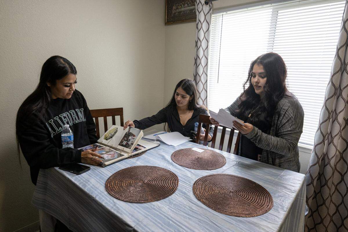 Briana Hernandez, a la izquierda, Patrisia Reyna y Silvia Reyna, a la derecha, las hijas de Silvia Reyna, hojean un álbum familiar en el apartamento de su madre en Corning el 2 de octubre. Silvia Reyna, una inmigrante indocumentada de México, fue detenida por Immigration and Customs Enforcement durante su cita programada meses después de presentar una denuncia por acoso sexual contra un hombre que trabajaba para ICE.