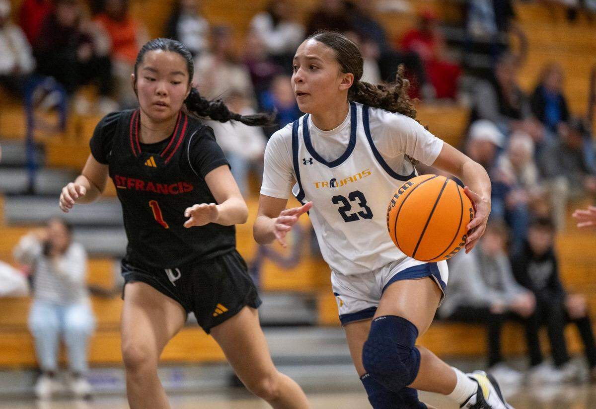 The Oak Ridge Trojans’ Vanessa Johnson (23) dribbles past the St. Francis Troubadours Karly Okamoto (1) in on Feb. 7.