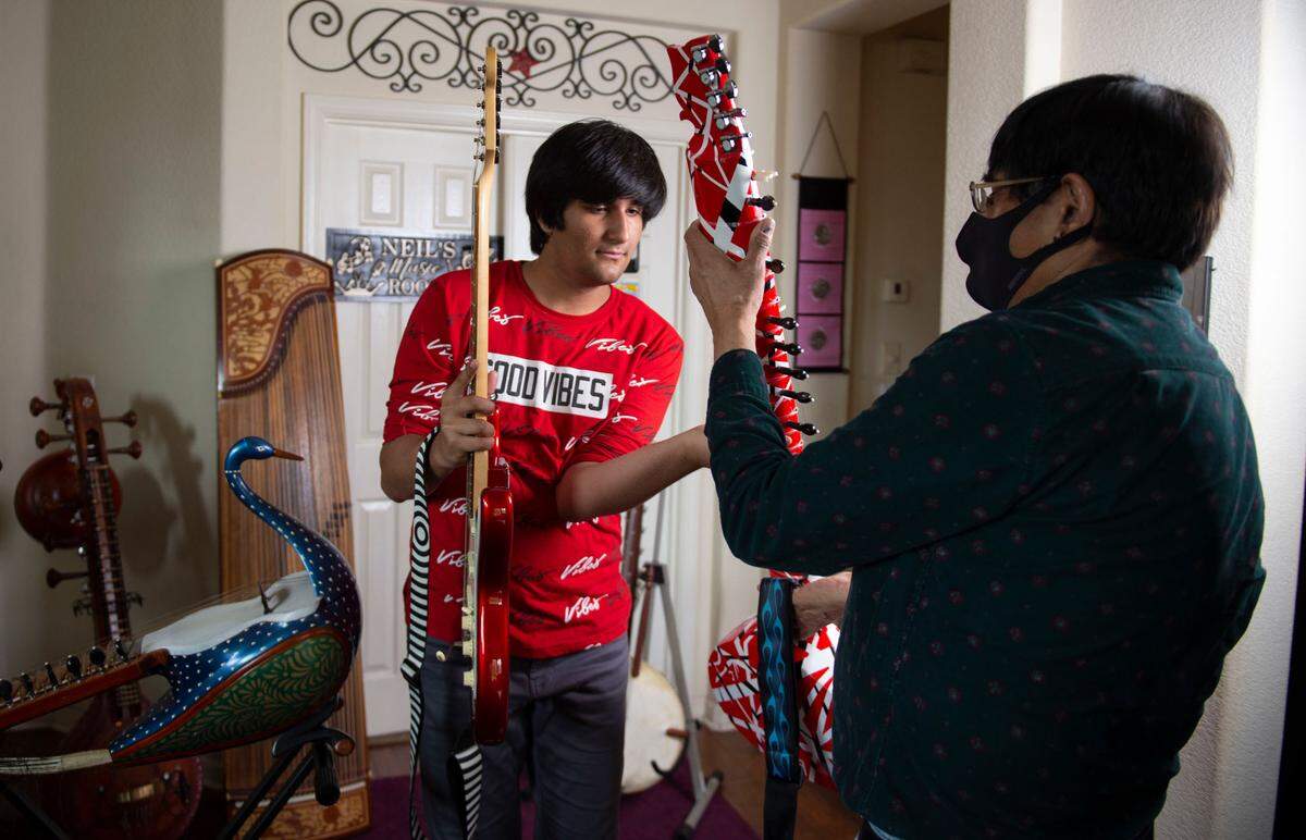 Musical prodigy Neil Nayyar hands an instrument to his father Rajan Nayyar while playing in his living room in Elk Grove. “Every instrument was different,” Rajan said. “Drums, piano, then to flute, to saxophones.”