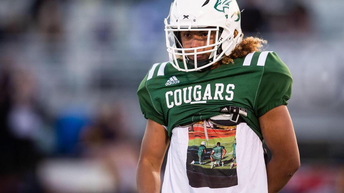 Kennedy’s Xavier Calvin listens to words honoring Manny Antwi, his teammate and friend who died during their home opener, as he wears a t-shirt in Antwi’s memory during halftime at their high school football game against River City on Thursday, April 15, 2021, at John F. Kennedy High School in Sacramento.