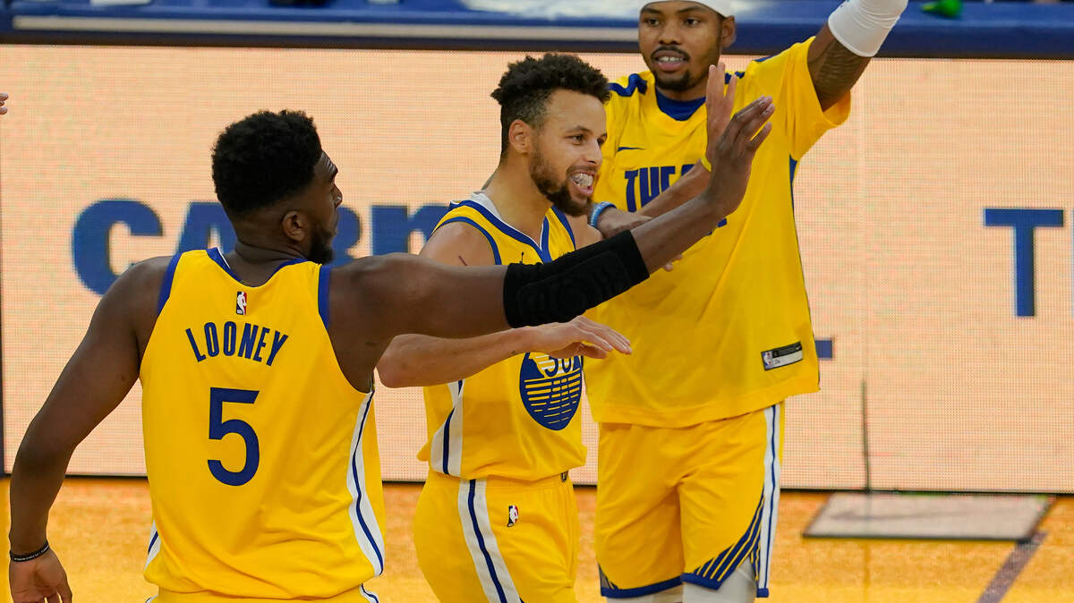Golden State Warriors guard Stephen Curry, center, is congratulated by forwards Kevon Looney (5) and Kent Bazemore after scoring against the Sacramento Kings during the first half of an NBA basketball game in San Francisco, Monday, Jan. 4, 2021. (AP Photo/Jeff Chiu)