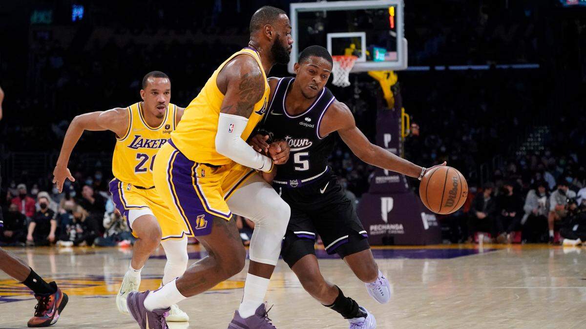 Sacramento Kings guard De’Aaron Fox (5) is defended by Los Angeles Lakers forward LeBron James during the second half of an NBA basketball game Tuesday, Jan. 4, 2022, in Los Angeles. (AP Photo/Marcio Jose Sanchez)
