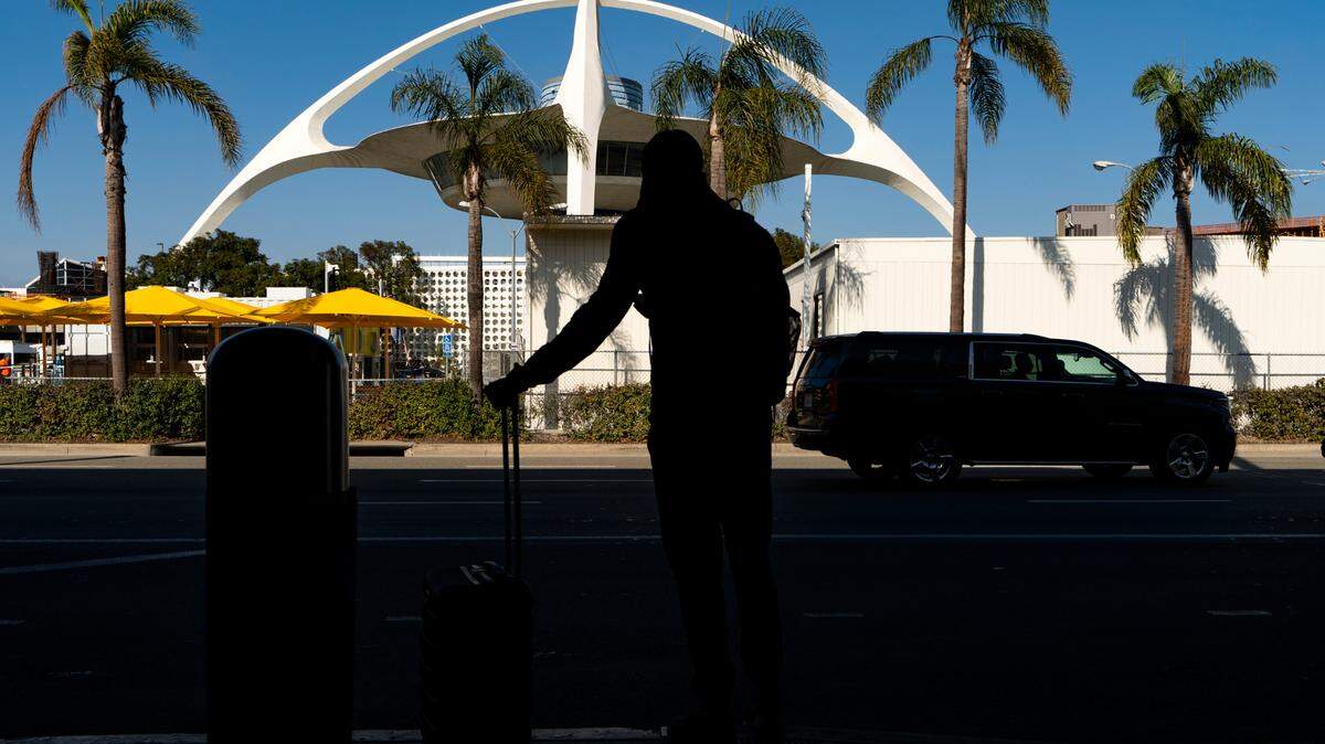 A travelers waits for a ride at the Los Angeles International Airport in Los Angeles Wednesday, Nov. 25, 2020. (AP Photo/Damian Dovarganes)