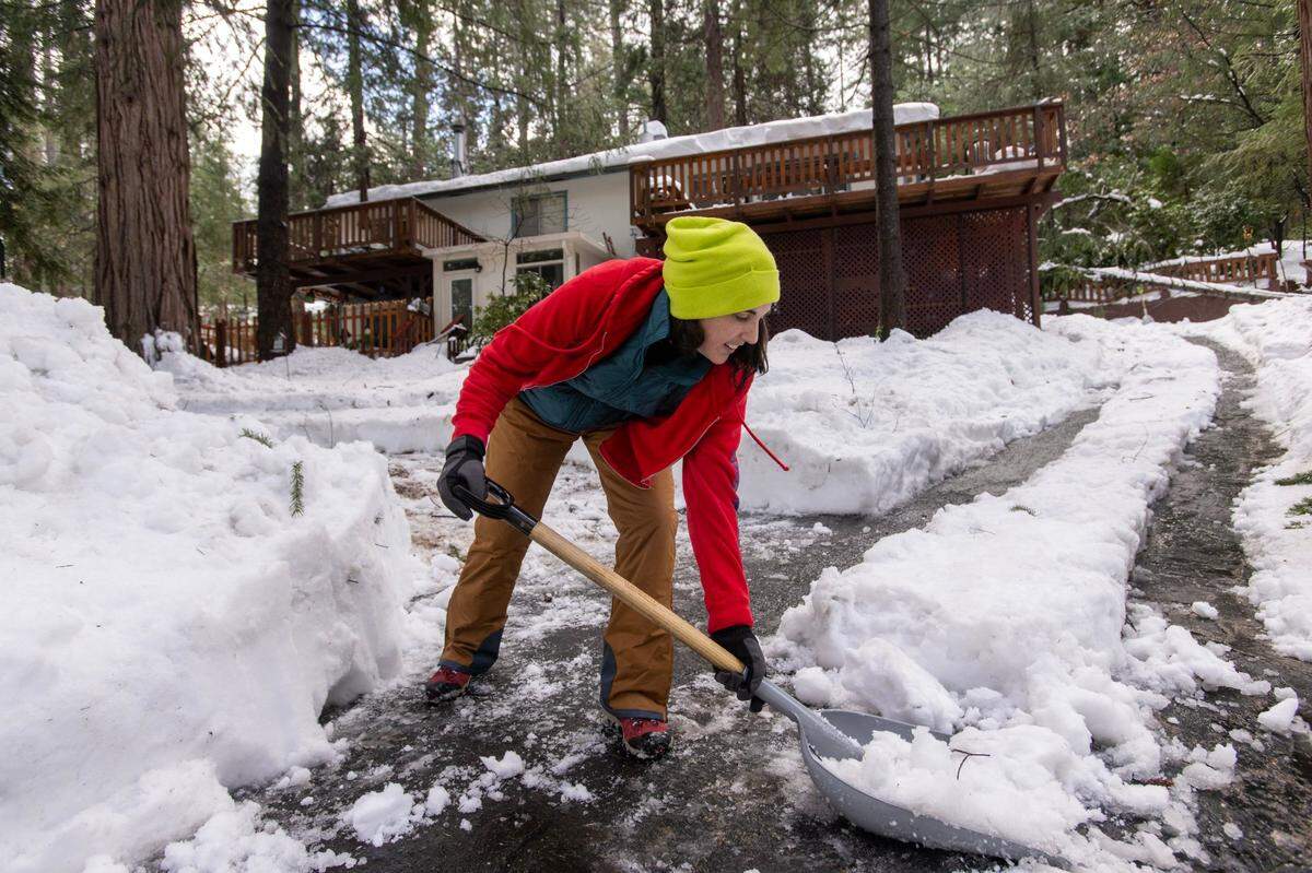 Alexis Berry clears the driveway to her home on Sunnyside Drive in Magra on Tuesday. She said her electricity has now been restored but her heat went out. “It’s 43 degrees inside my house right now,” said Berry.