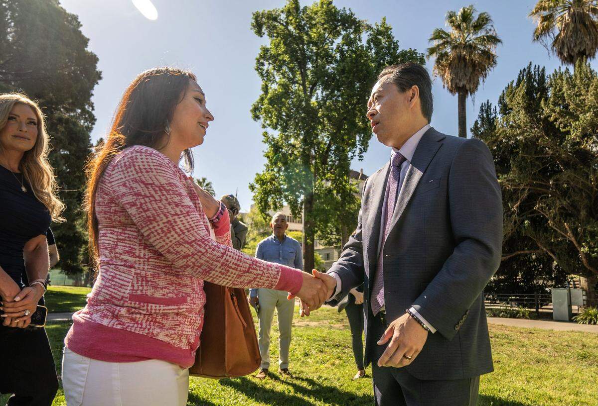 Sacramento County District Attorney Thien Ho, right, greets Regina Chavez at a press conference Aug. 14. Her 15-year-old daughter Jewels Wolf died of fentanyl poisoning.