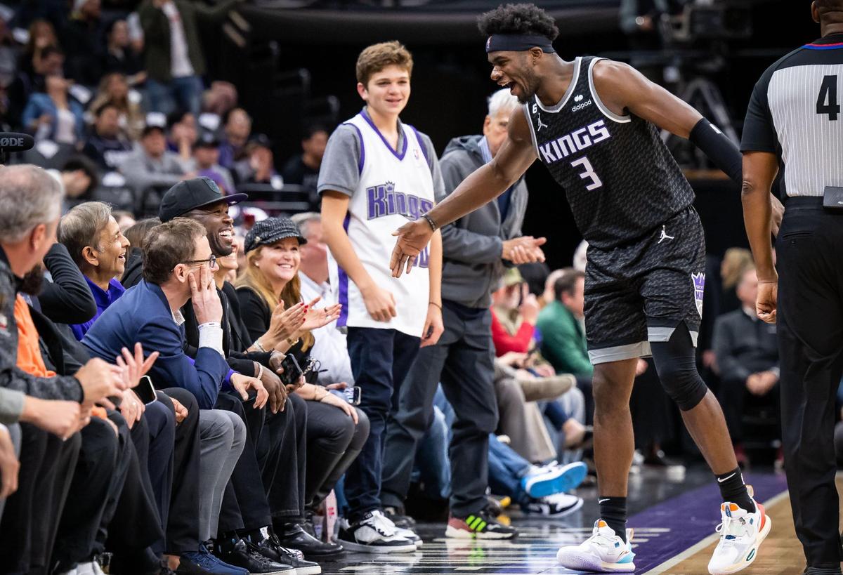 After a flurry of plays igniting the home crowd, Sacramento Kings guard Terence Davis II (3), right, is congratulated by rapper, businessman and actor 50 Cent (Curtis Jackson), seated by Sacramento Kings owner Vivek Ranadivé, in the third quarter of the NBA basketball game against the Indiana Pacers on Wednesday, Nov. 30, 2022, at Golden 1 Center in Sacramento.