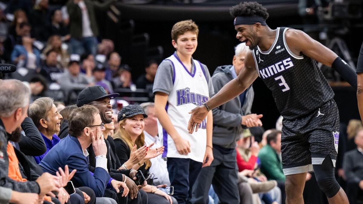 After a flurry of plays igniting the home crowd, Sacramento Kings guard Terence Davis II (3), right, is congratulated by rapper, businessman and actor 50 Cent (Curtis Jackson), seated by Sacramento Kings owner Vivek Ranadivé, in the third quarter of the NBA basketball game against the Indiana Pacers on Wednesday, Nov. 30, 2022, at Golden 1 Center in Sacramento.