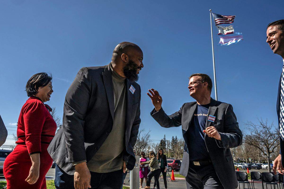 Sacramento City Unified School Board President Chinua Rhodes, left, and transgender advocate Evan Minton, right, celebrate the raising of the trangender flag after a press conference at the district’s headquarters in south Sacramento on Monday.&nbsp;