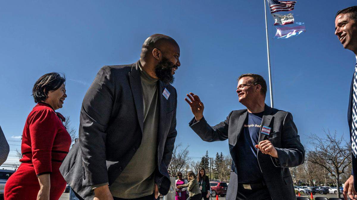 Sacramento City Unified School Board President Chinua Rhodes, left, and transgender advocate Evan Minton, right, celebrate the raising of the transgender flag at the district’s headquarters in south Sacramento on Monday, March 20, 2023. 