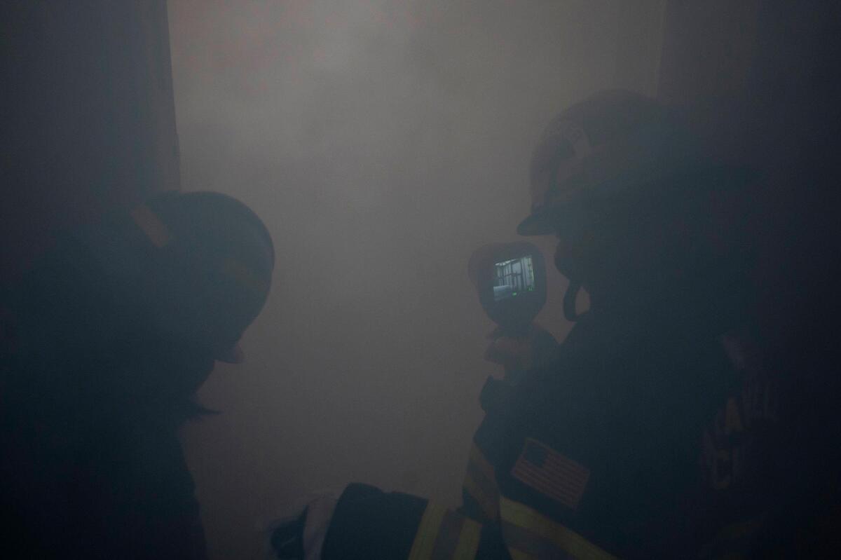Cailei Caldera, right, 17, uses a thermal imaging camera to scan the smoke-filled room to search for a person while Lacey Mayeux, left, 16, waits to enter during the HERo Girls Fire Camp, hosted by the Cosumnes Fire Department, on Sunday.