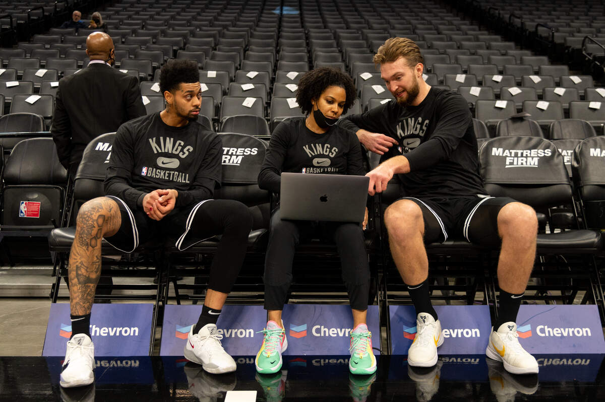 Sacramento Kings center Domantas Sabonis, right, guard Jeremy Lamb talk with assistant coach Lindsey Harding before a game at Golden 1 Center in 2022.