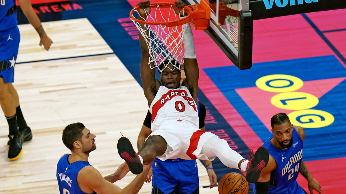 Toronto Raptors guard Terence Davis (0) follows through on a slam dunk over Orlando Magic center Nikola Vucevic (9) and center Khem Birch (24) during the first half of an NBA basketball game Sunday, Jan. 31, 2021, in Tampa, Fla. (AP Photo/Chris O’Meara)