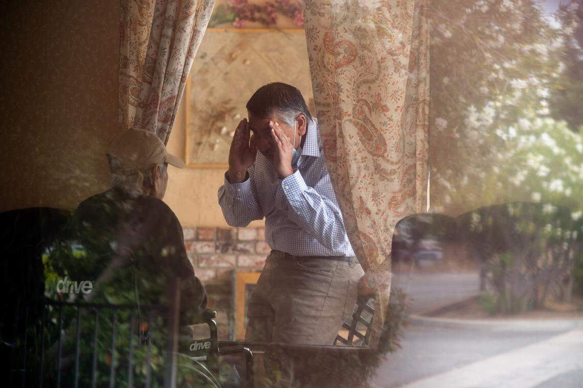 Raj Dosanjh of Fresno visits with his dad, Ajaib Dosanjh, 87, through a viewing window at City Creek Post Acute on May 14, 2020, in south Sacramento. Raj said he became discouraged after weeks of restricted contact due to coronavirus precautions and said his dad became depressed because of lack of family contact. Ajaib died in June, two months before the first cases of COVID-19 were detected at the facility, formerly known as Saint Claire’s Nursing Center.