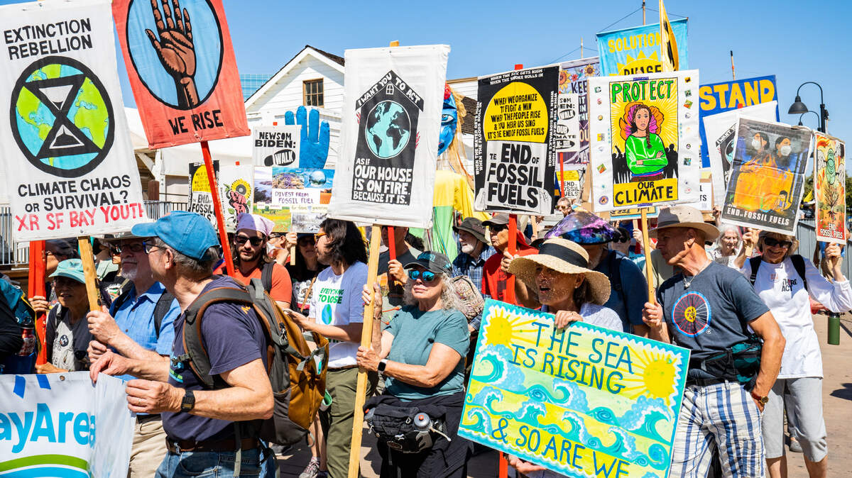 Manifestantes marchan por Old Sacramento llevando pancartas que piden protección del clima y el fin de los combustibles fósiles,  el domingo 17 de septiembre de 2023.