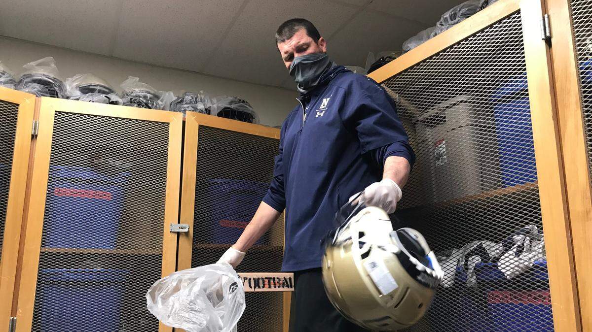 Elk Grove coach John Heffernan hands out gear to players before the first day of practice earlier this week.