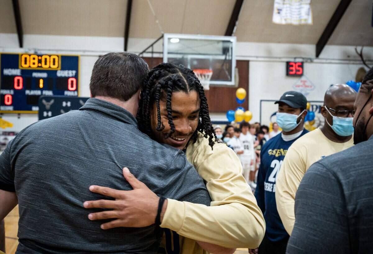 Elk Grove standout guard Ameere Britton (20) gets a hug from head coach Dustin Monday after being recognized on senior night ahead of their game against Cosumnes Oaks at the high school boys basketball matchup Feb. 4, at Elk Grove High School. The Thundering Herd beat the Wolfpack 81-58 at home in Elk Grove.