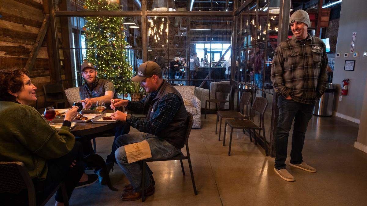 Dust Bowl Brewing Company co-owner Brett Honoré, right, visits with Karen Tate, whose husband is co-owner Brett Tate, and brothers Lars and Colin Russell, at Dust Bowl’s Old Town Tap House in Elk Grove on Dec. 18, 2021. Dust Bowl is pairing specialty beer with five flavors of Girl Scout cookies during March.