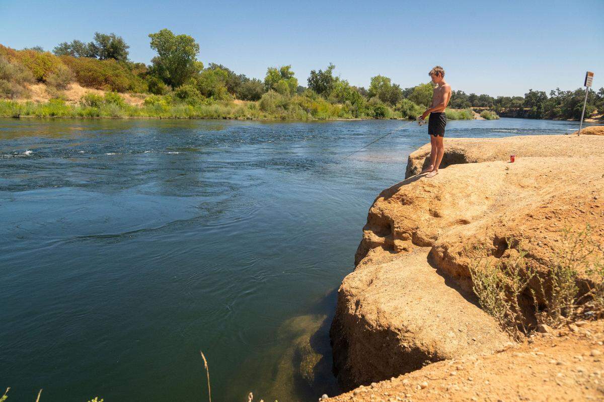 Davis Bryant, 15, fishes from the Clay Banks along the American River in Rancho Cordova on Friday, the day the county prohibited jumping and diving at the location. Bryant, who is from the Bay Area, said he has enjoyed jumping off the banks in the past.