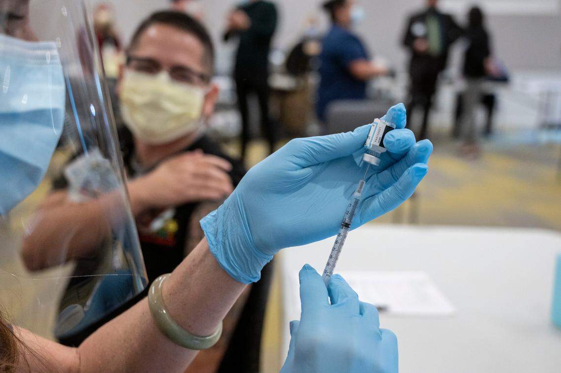 Claudio Alvarado, left, a registered nurse at UC Davis Medical Center, waits to be inoculated with the Pfizer-BioNTech COVID-19 vaccine by Heather Donaldson, registered nurse at UC Davis Medical Center, Tuesday, Dec. 15, 2020 in Sacramento.