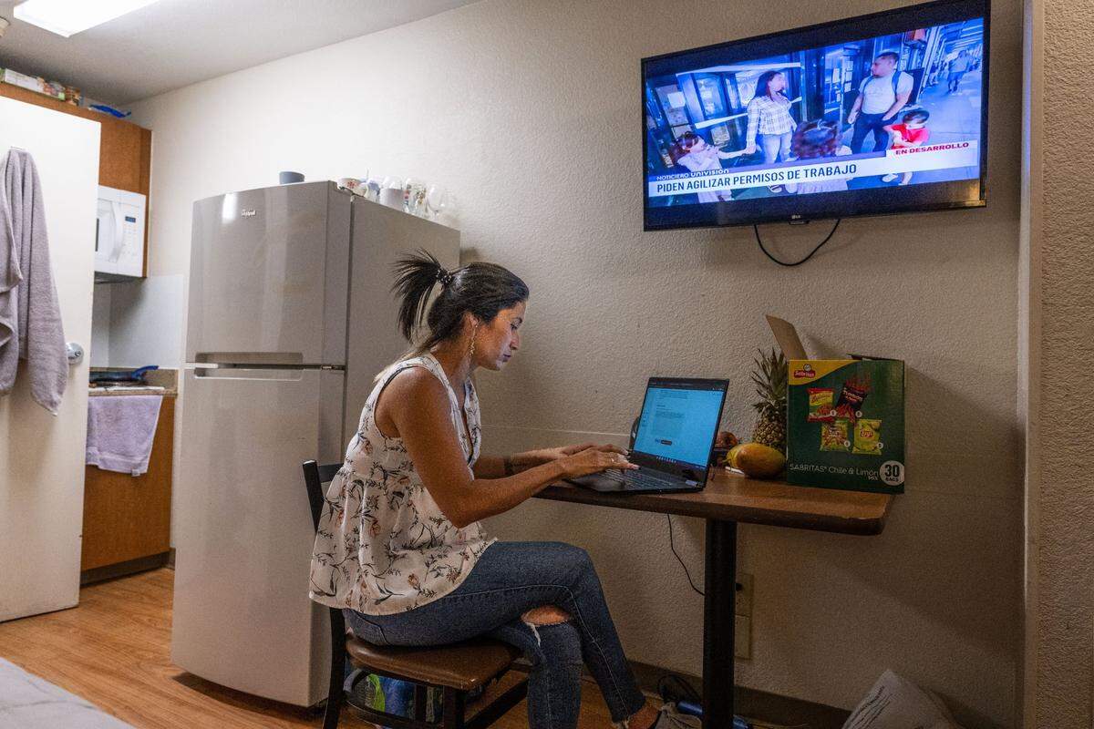 Aura, 31, of Colombia, one of the migrants that arrived in Sacramento earlier this summer from Texas, looks in August at the website to apply for asylum as a national Spanish television network runs a story on migrants in New York. Aura and other migrants struggle with the decision to seek asylum as it could potentially be the start of a deportation order.