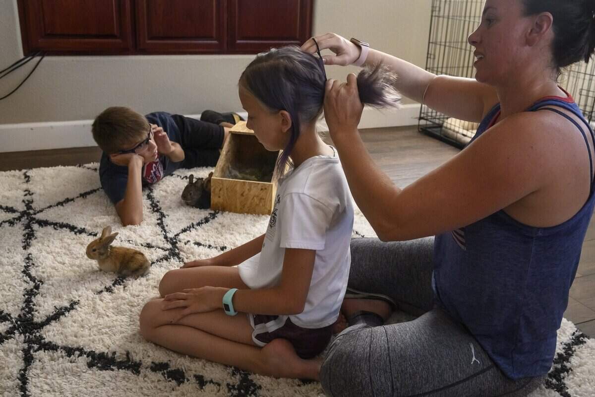 Elisha Nelson fixes the hair of daughter Natalya, 10, while her son Zachary, 11, plays with new baby bunnies in their home in Woodland on June 25. Nelson, who wears a prosthetic arm at home, spoke of the sacrifices she has made in balancing training and spending time with her family. “I’m competing every weekend right now and I’m going to be missing some of my son’s baseball games and things but they know its to follow my dream, but it’s hard,” she said.