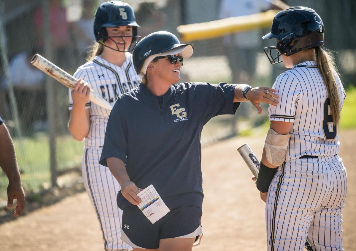 Elk Grove Thundering Herd head coach Amanda Buck, center, motivates Brooke Hanson (8) during a rally in the fourth inning against Rodriguez (Fairfield) at the high school girls softball CIF Sac-Joaquin Section Division II first round playoff game Tuesday, May 16, 2023, at Elk Grove High School. The Thundering Herd beat the Mustangs, 8-1.