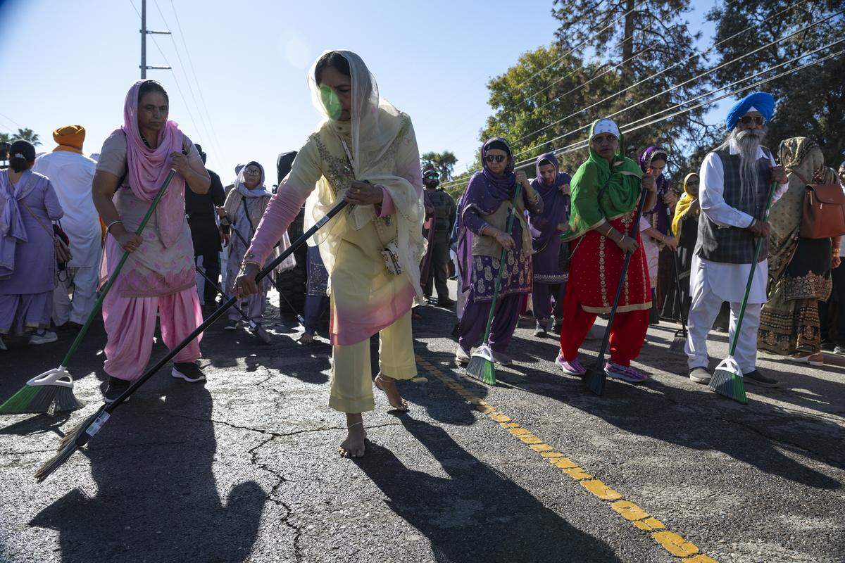Women sweep the ground before the main float during Nagar Kirtan, also known as the Sikh Parade, in Sutter County on Sunday, Nov. 2, 2025.