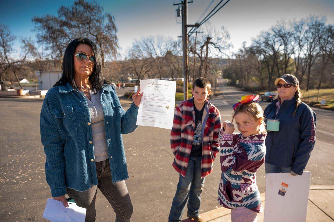 Jill Boswell, left, of Shingle Springs, holds on Monday a “notice of health exclusion” given to her children Leo, 10 and Kassidy, 7, for violating the state mask mandate at Buckeye Elementary School. Both were sent home because they would not wear a mask. The family and supporters protest every day in front of the school before school starts.