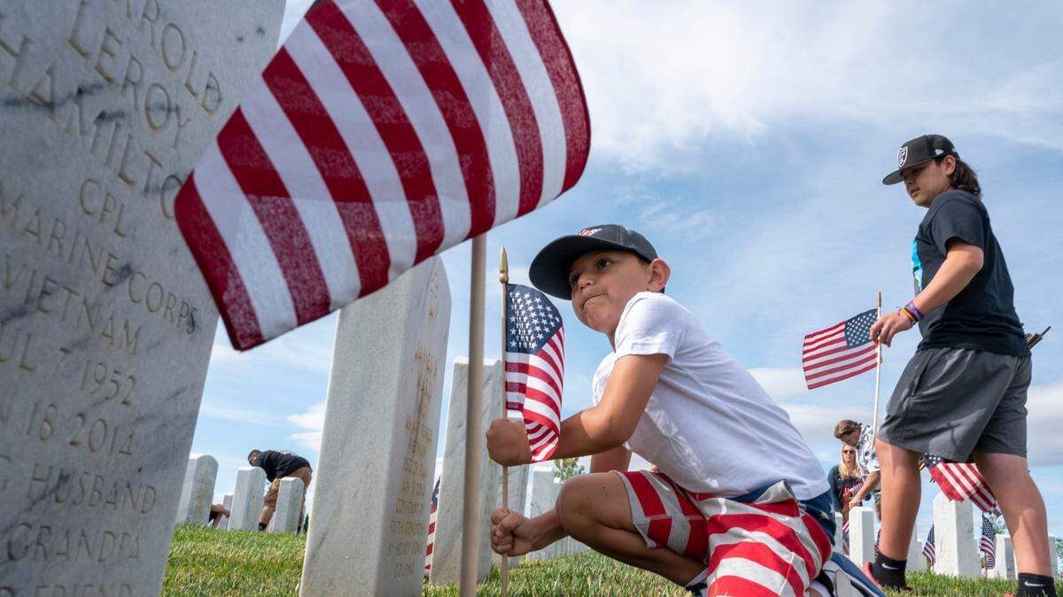 Derrick Garcia, 6, of Winters, uses his might to place a lawn flag as his family, including brother Anthony, 12, right, put flags in front of headstones at the Sacramento Valley National Cemetery in Dixon as part of the Memorial Day ceremony Saturday, May 28, 2022.