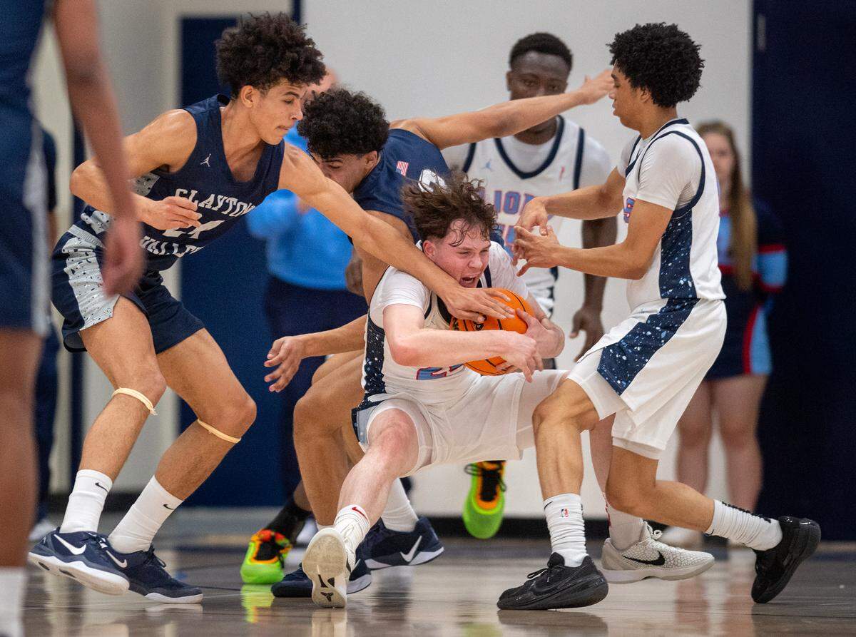 The Destiny Christian Lions’ Jaylen Valdez (24) secures a loose ball between teammate Frederick Blue (0) and the Clayton Valley Charter Ugly Eagles’ Zion Grissom (24) in the first half of the CIF Northern California Division Il semifinal game on Saturday.