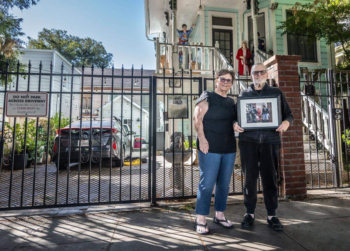 Barbara Holmes and Tom Williams, the owners of the former home of the infamous Dorothea Puente at 1426 F Street in Sacramento, pose on Friday, Oct. 18, 2024, in front of the house with a Sacramento Bee news photograph of the late serial killer leaving the scene during the police investigation.