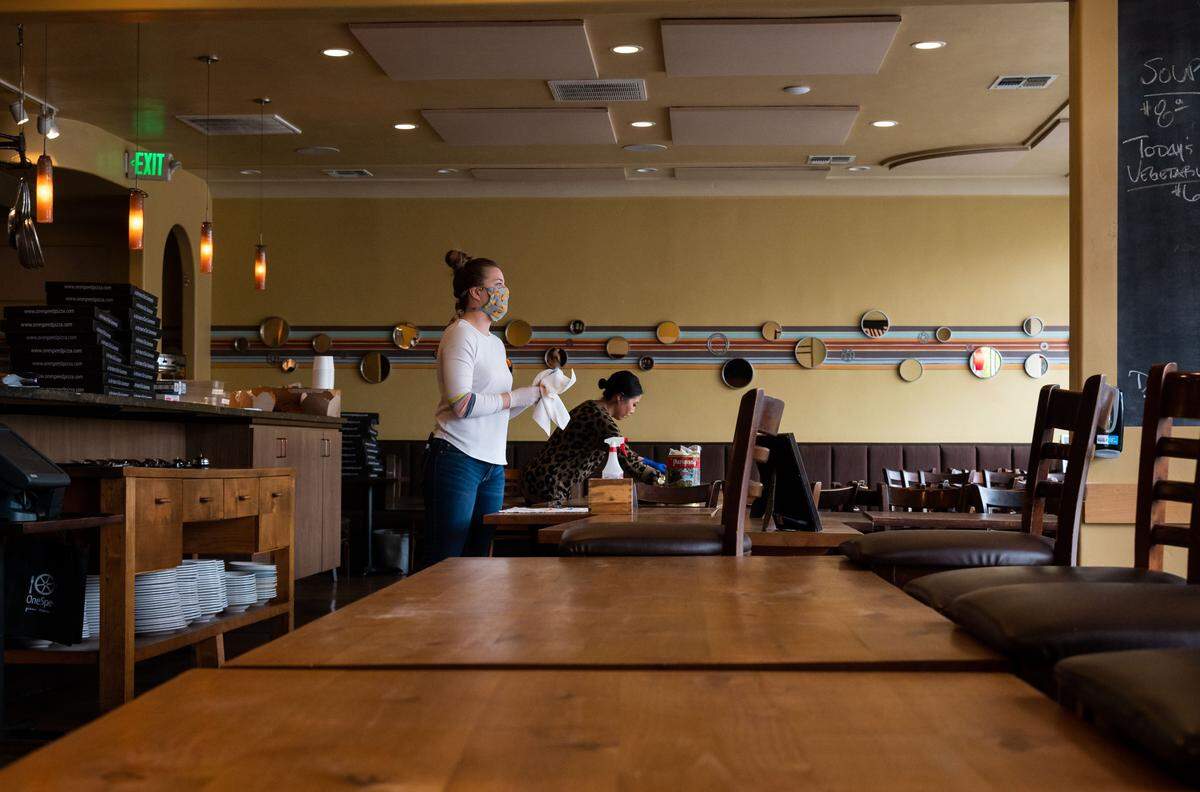 Sara Trana, left, manager at OneSpeed restaurant owned by chef Rick Mahan, sanitizes near a takeout interaction area Wednesday, April 8, 2020, in East Sacramento. “We’re sanitizing after every single contact. We’re doing everything in our power to make sure that we’re staying safe as well as our customers,” she said from the closed dining room.
