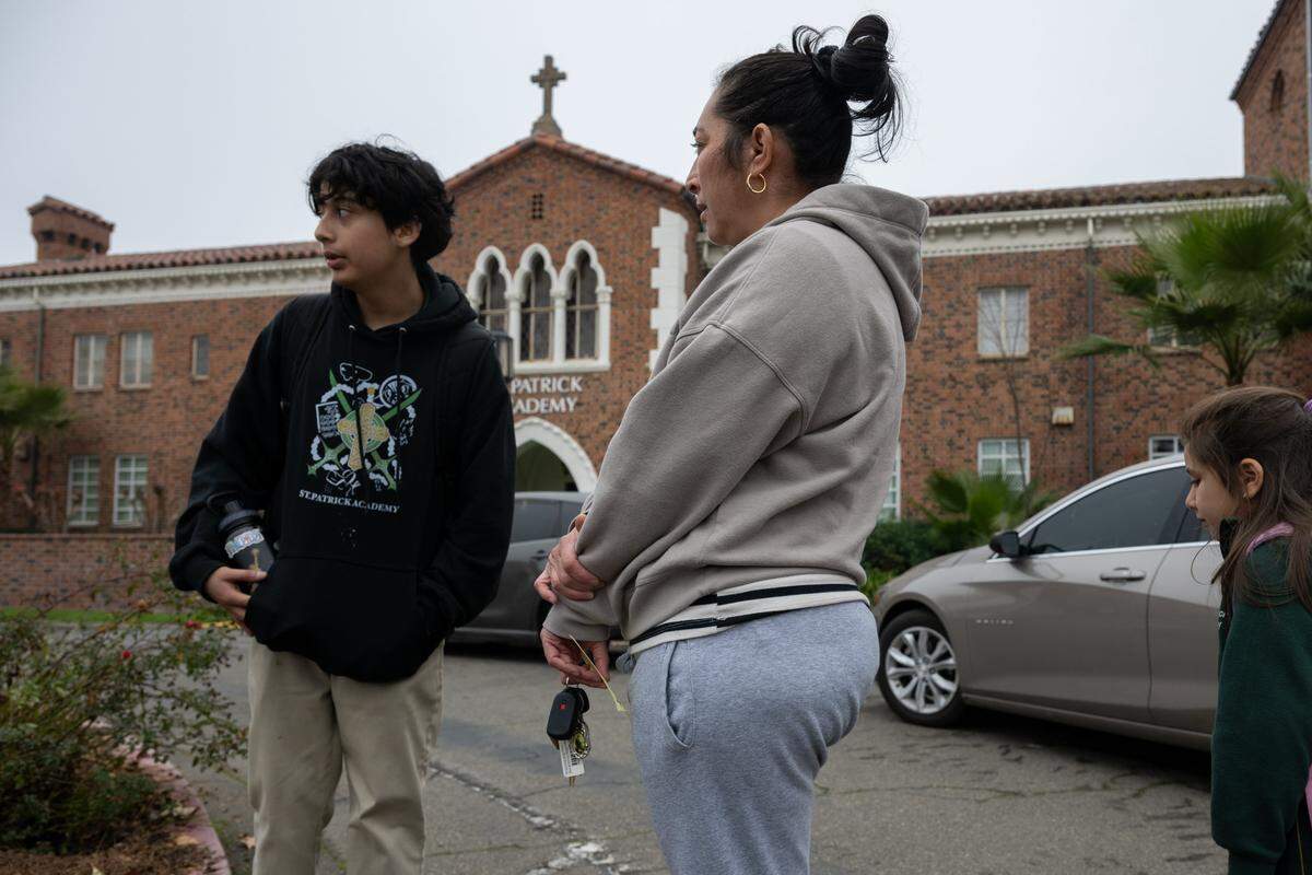 Glenda Rubio stands at St. Patrick Academy in Sacramento on Friday with her children, eighth grader Diego Benavides, 14, and second grader Juliana Benavides, 8. The siblings have attended the Catholic campus, which the diocese announced will close at the end of the school year, since kindergarten and preschool, respectively.
