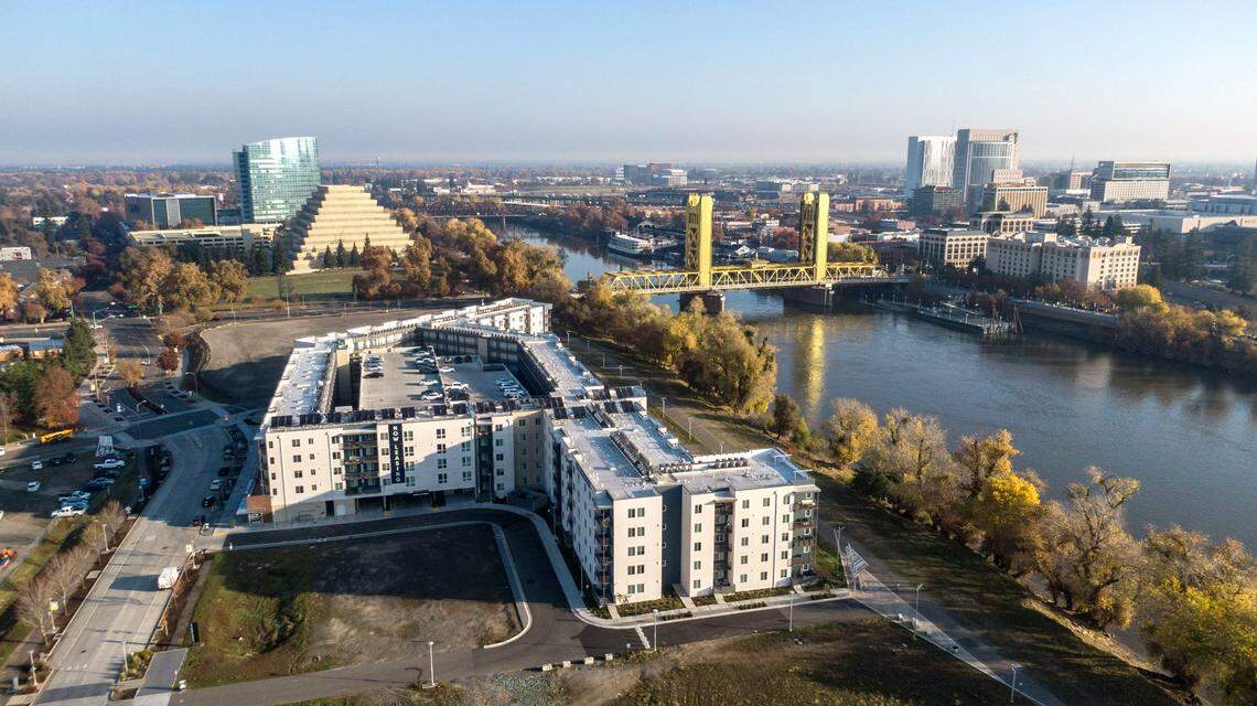 The Tower Bridge and the ziggurat building stand behind the recently opened 805 Riverfront apartments in West Sacramento in a drone photograph from Dec. 6, 2024. 