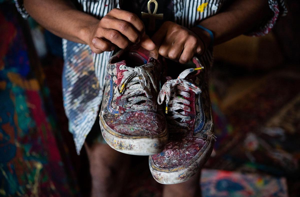 Halcyon Clay, an artist who has lived in California for about three years, said he was introduced to art through an ARTreach van. He holds a pair of shoes, that over time have collected paint splatter from his work, during an interview Thursday, Feb. 4, 2021, at a loft in the the WAL building in midtown Sacramento.