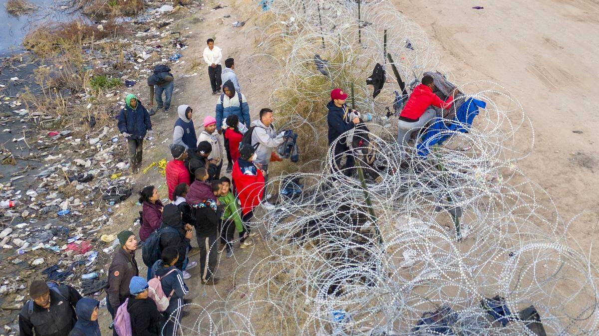 Immigrants try to pass over razor wire after crossing the border into El Paso, Texas from Ciudad Juarez, Mexico. Those who managed to get through the wire were then allowed to proceed for further processing by U.S. Border Patrol agents. (John Moore/Getty Images/TNS)