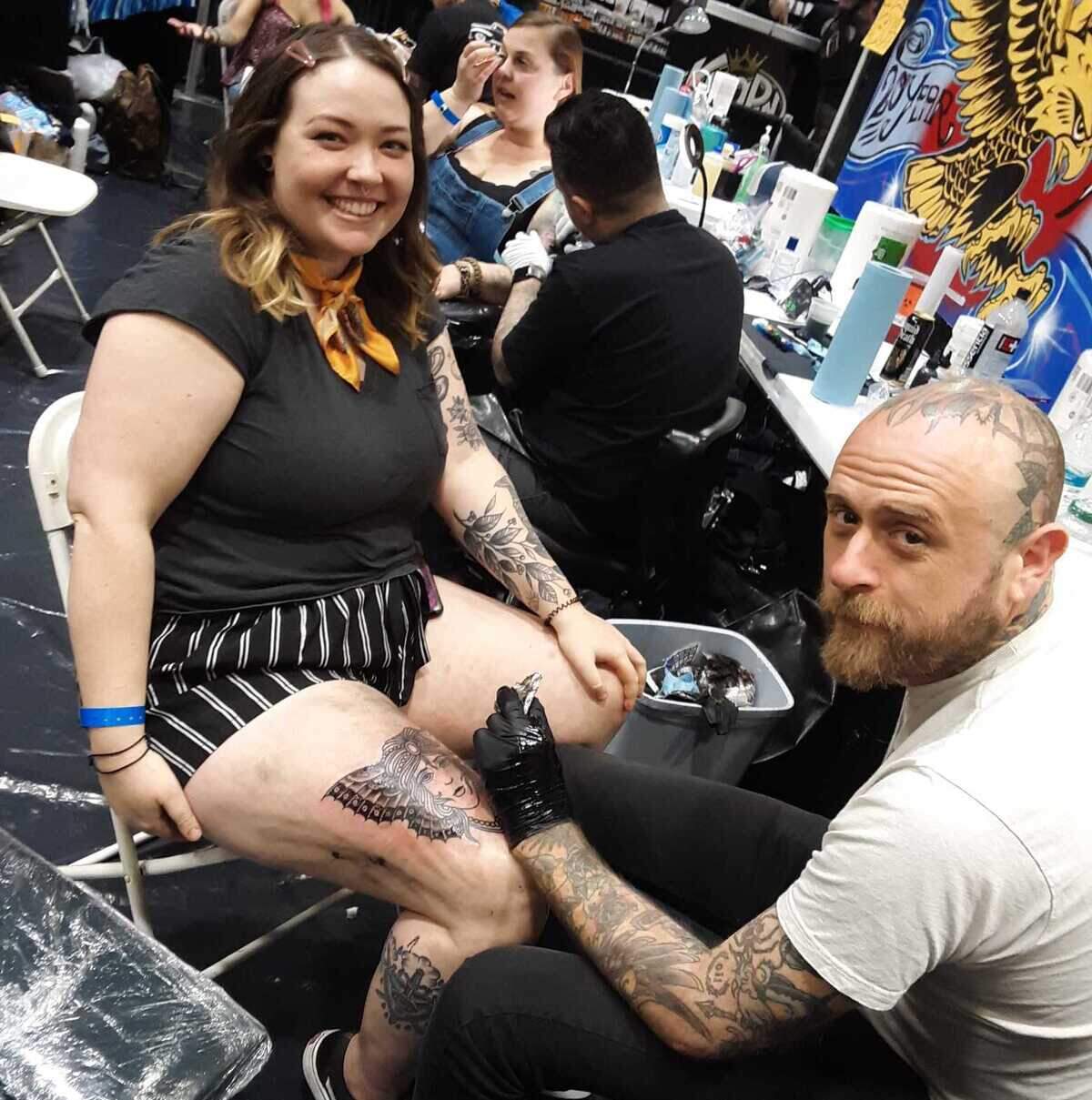 Emily Rowe of Sacramento get a fresh tattoo on her leg from Sacramento tattoo artist Nate Daskalos of Forever Tattoo at the first Capitol City Classic tattoo convention Saturday, May 7, 2022, at the SAFE Credit Union Convention Center in Sacramento, Calif.