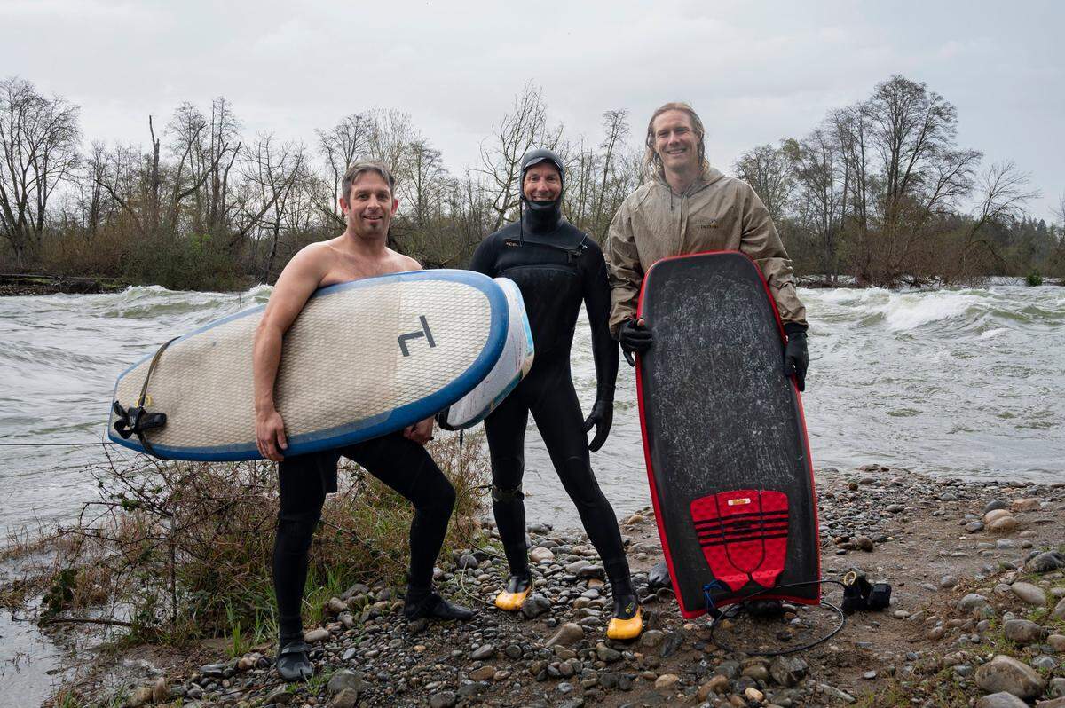 Mark Divittorio, left, Steve Sylvester, center, and Tyler Lausten take a break from river surfing on Sunday, March 12, 2023, at the American River near Carmichael.