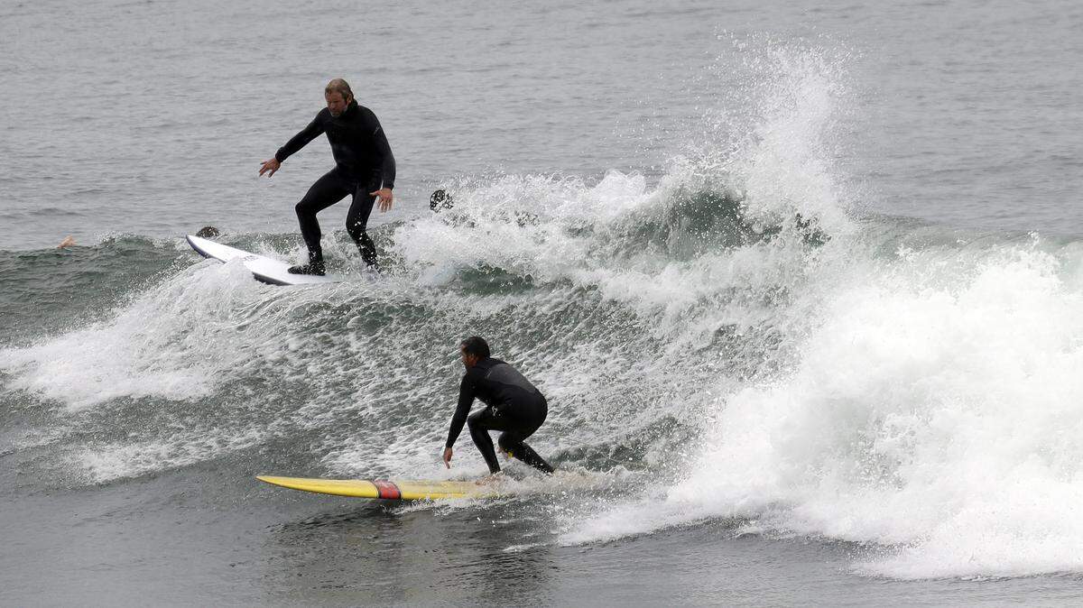 Surfers share a wave at Pleasure Point in Santa Cruz in 2017. It’s not so laid-back at the University of California, Santa Cruz, where a housing crunch for students has administrators asking professors and employees to rent out rooms this fall.