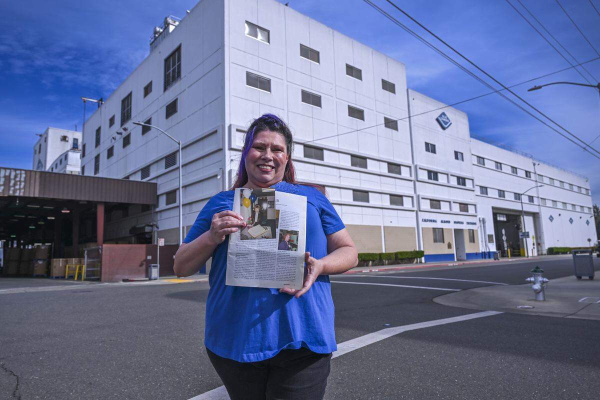 Cristy Rudkin, a production associate at Blue Diamond, holds a photo and newsletter of her grandmother and mother — who were both Blue Diamond employees — as she stands outside the plant on Nov. 11. According to Rudkin, at least one of her family members has been employed at the plant since 1963.