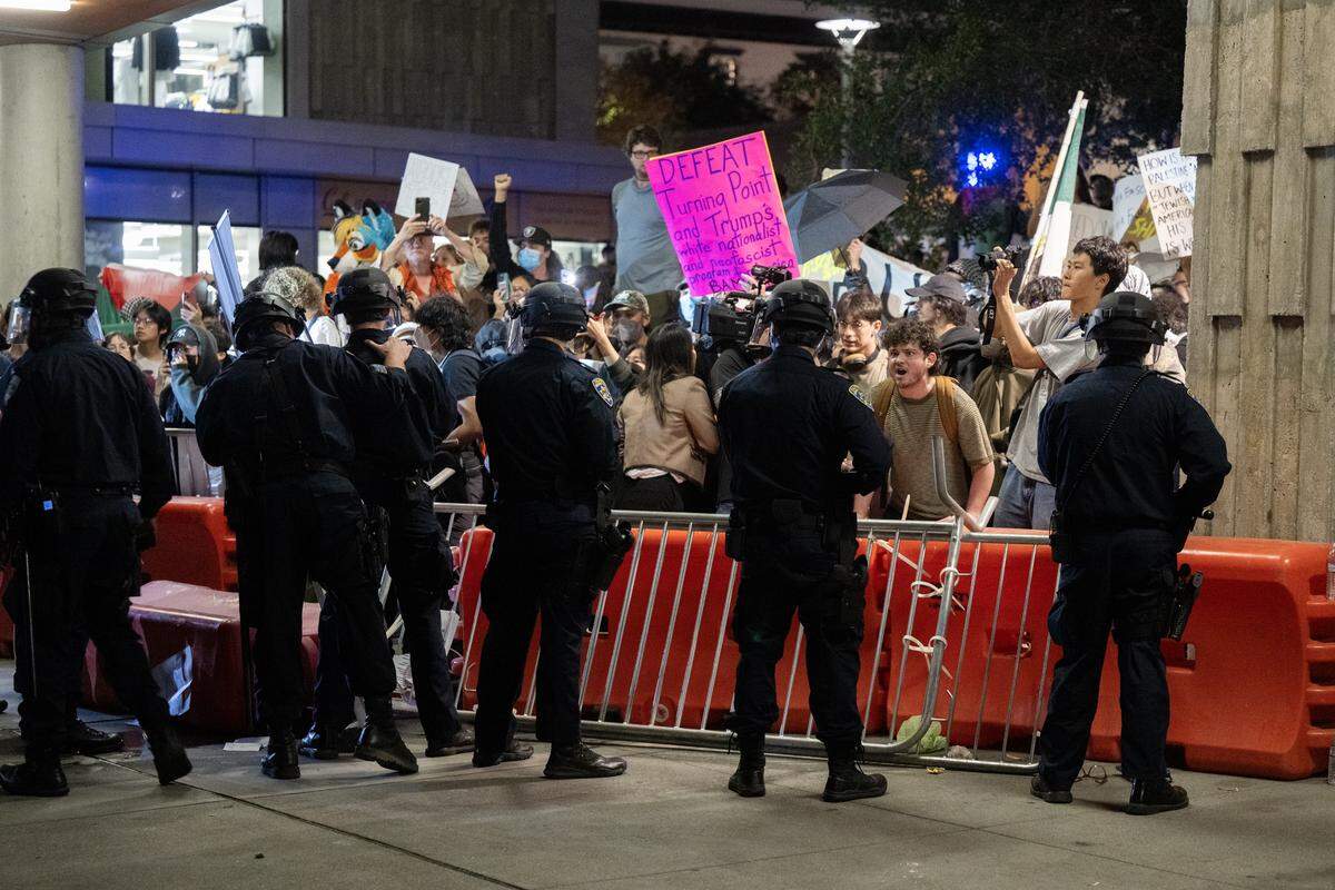 Police watch protesters chant back and forth with people lining up to attend a Turning Point USA tour event at UC Berkeley on Monday, Nov. 10, 2025. 