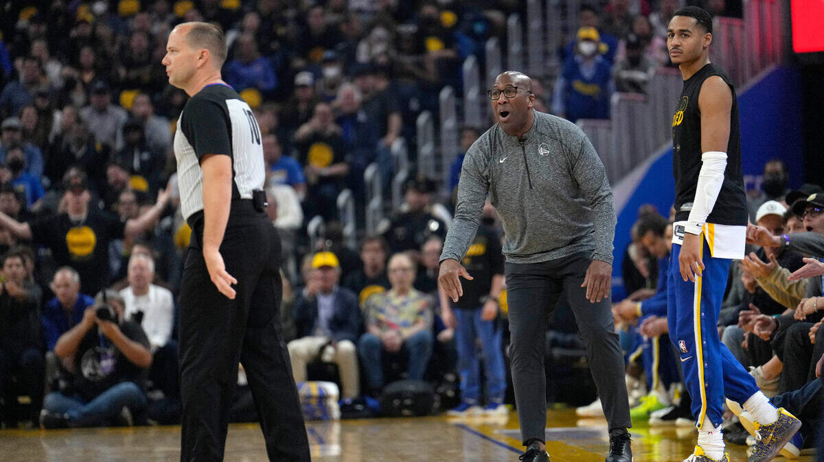 Golden State Warriors assistant coach Mike Brown, center, argues with the referee, left, as Warriors guard Jordan Poole, right, looks on during the first half of Game 4 of an NBA basketball Western Conference playoff semifinal against the Memphis Grizzlies in San Francisco, Monday, May 9, 2022. Brown is filling in for head coach Steve Kerr who tested positive for COVID-19. (AP Photo/Tony Avelar)