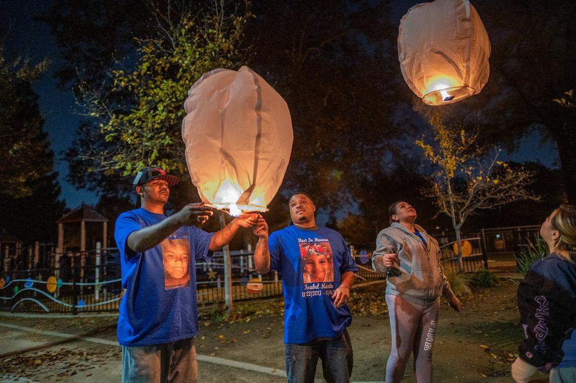 Brandon Martin, left, and Monica Delgadillo, right, release two lanterns in Sacramento’s Southside Park on Monday, Nov. 22, 2021, representing the birth and death of their daughter, Isabel Agnes Delgadillo Martin, who was was shot and killed earlier this month. The day would have been Isabel’s eighth birthday. Family friend Ceasar Garner, center, and her father wore T-shirts with her picture on them.