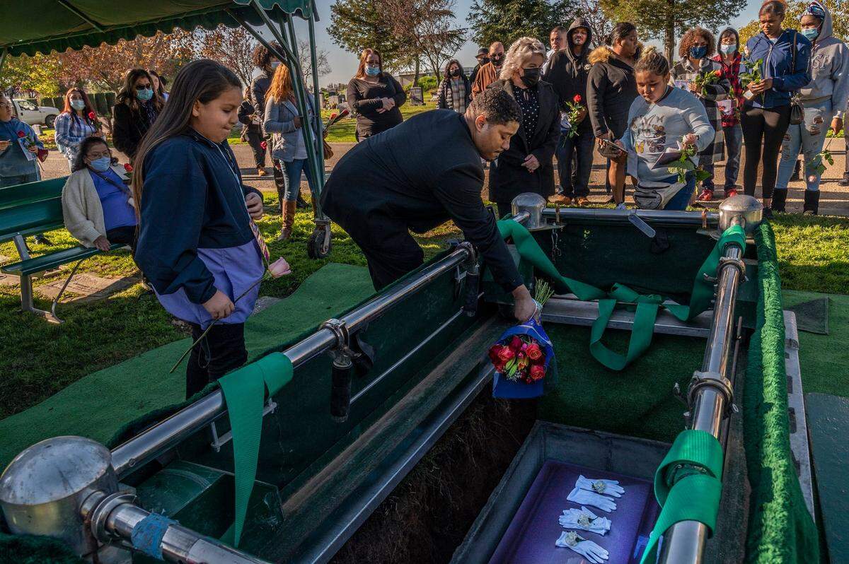 Mariah Delgadillo, 10, left, holds a rose for her cousin Isabel Delgadillo Martin’s casket as longtime family friend Caesar Gardner tosses a bouquet at her funeral. Isabel’s uncle, Tyrice Martin, 22, has been charged in connection with the shooting.