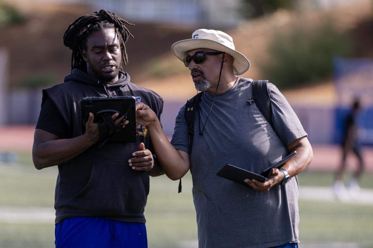 Grant Pacers co-head coaches Syd Thompson, left, and Carl Reed look at their tablets during practice on campus in Del Paso Heights on Tuesday.