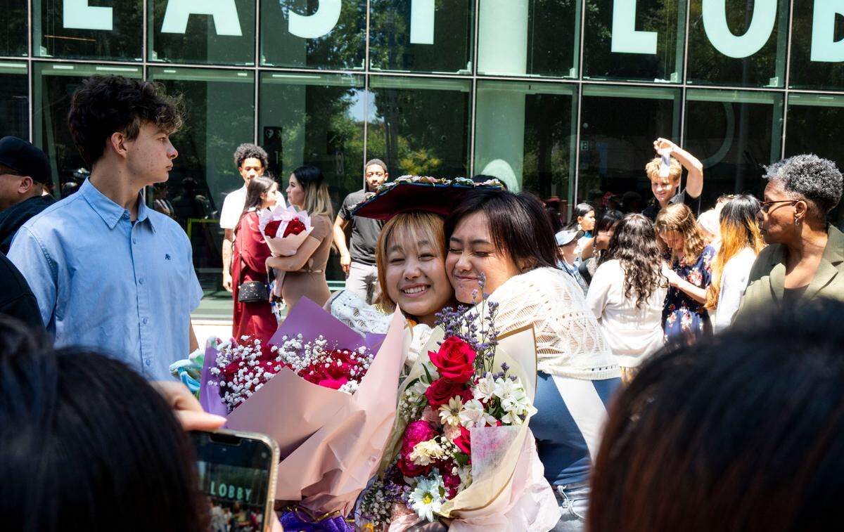 Sisters Sandra Xiong, left, and Suzie Xiong, right, pose for a picture at the Hiram Johnson High School graduation on June 11, 2025.