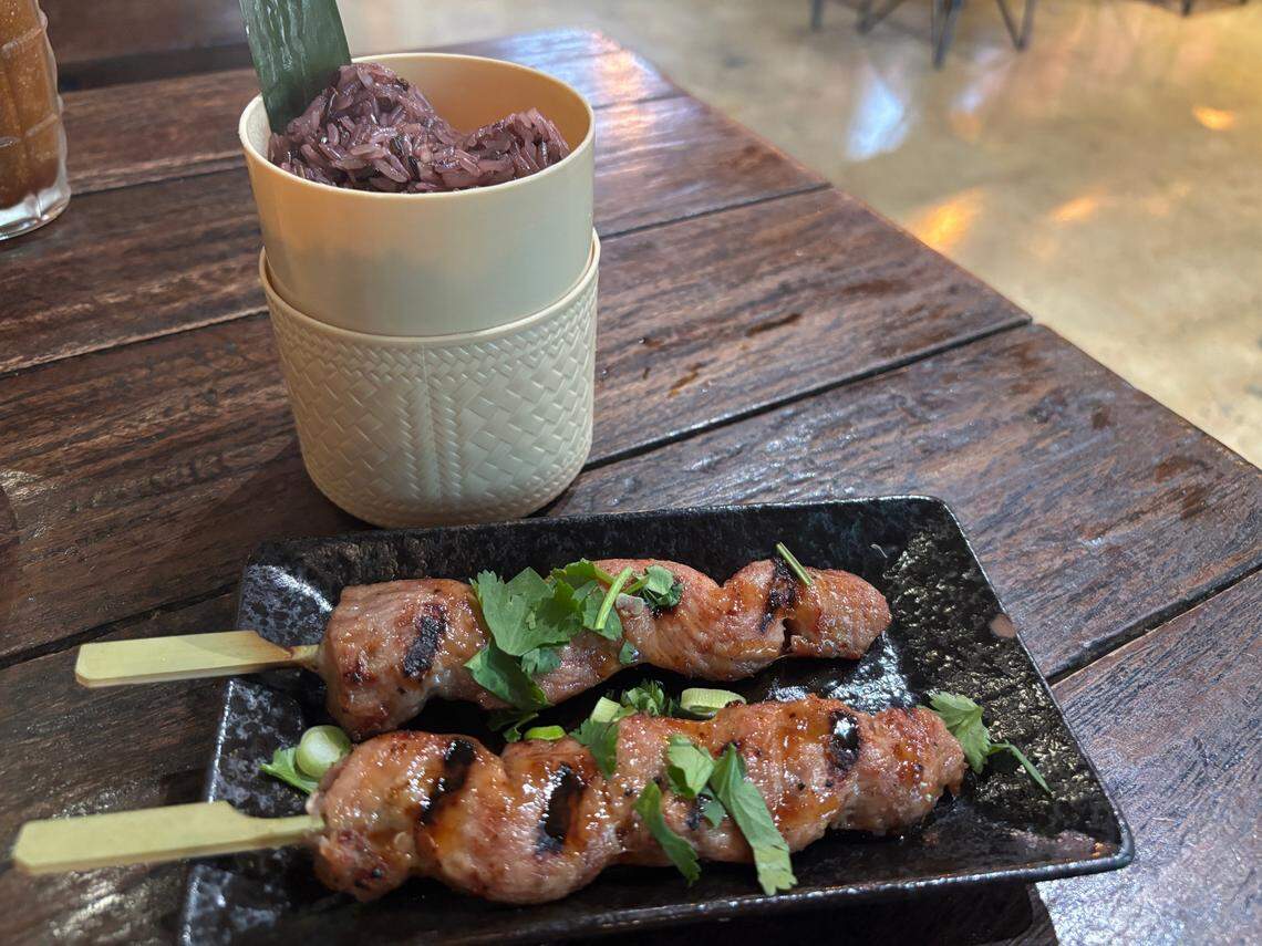 A slightly spicy sauce coats Moo Ping pork skewers at Kin Thai Street Eatery, and black sticky rice softens the pork’s intense umami flavor.